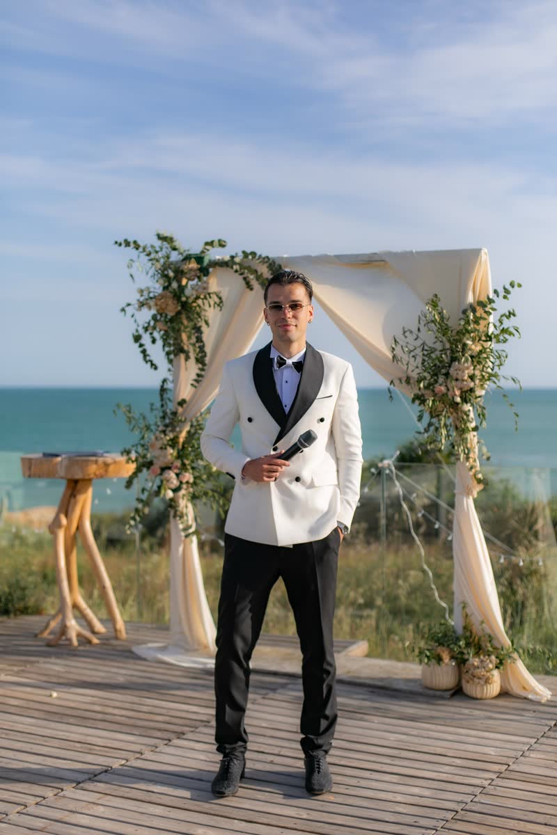 Vova standing beneath a flower arch with the sea behind him