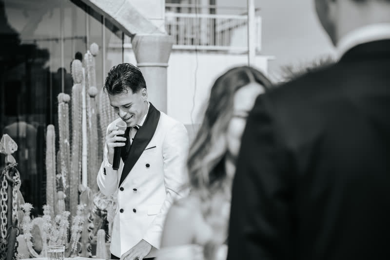 Black and white photograph of Vova hosting beside the couple